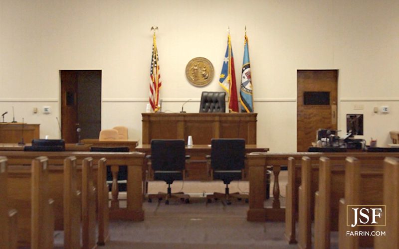 The interior of a North Carolina courtroom with flags and the state seal.